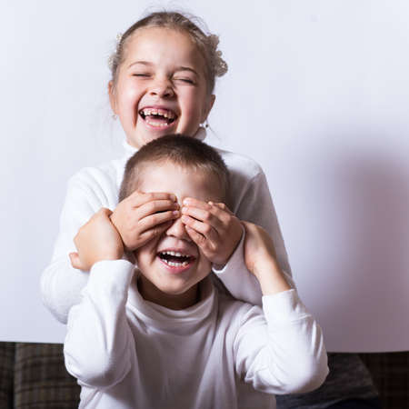 Happy sister and brother laugh and surprise each other at homeの写真素材
