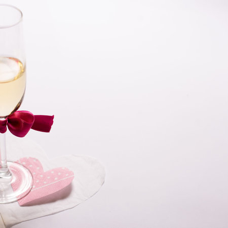Celebrating Valentine's Day, glass of white wine and heart shaped napkin on a white backgroundの写真素材