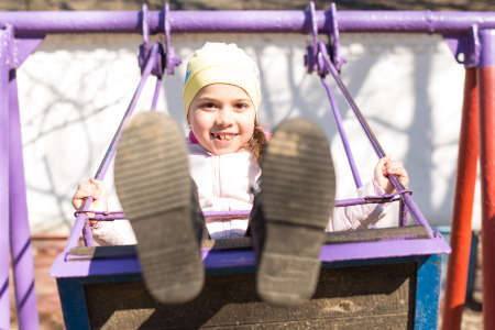 The girl is riding on a swing. Children in spring go en sports fields instead of smartphonesの写真素材