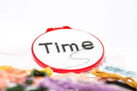 Word time embroidered on white with beads and different threads for embroidery on a white...