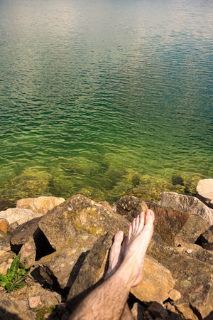 Lake with clean cold water and mans lags on a frontの写真素材