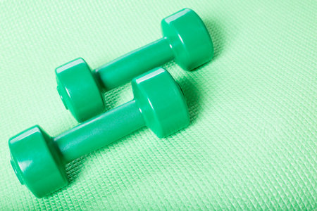 Green dumbbells on fitnes carpet with space for text