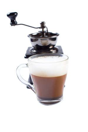 Making italian cuppuccino with manual coffee grinder and turk. Cup of cuppuccino in focus and manual coffee grinder on background, isolated on a white.の写真素材