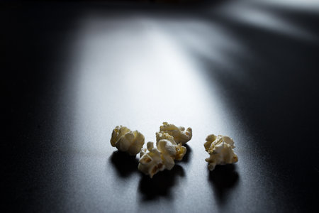 Popcorn flakes close-up on black background and light came from screen of monitor.の写真素材