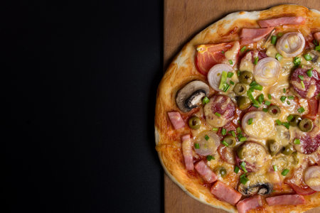 Ready pizza on kitchen board, on black background with copy space.の写真素材