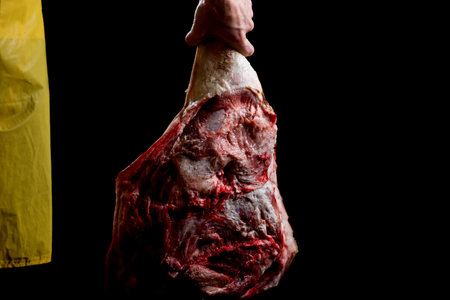 Butcher holding pork thigh in hand, isolated on black.の写真素材