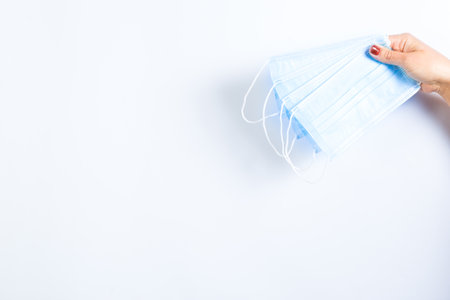 Woman's hand holding medical masks on a white background with copy space.の写真素材