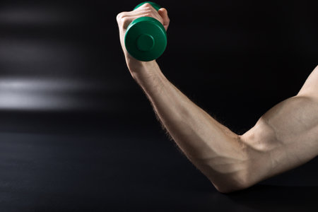 Male hand with dumbbell close up, on black background.の写真素材