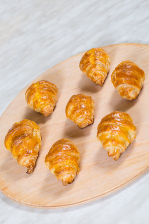Frech golden baked croissants on wooden plate, close up.