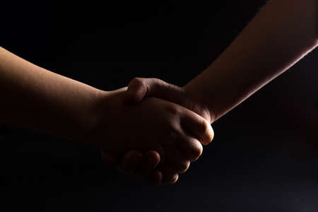 Handshake of children's hands, Children hands close up on black background.の写真素材