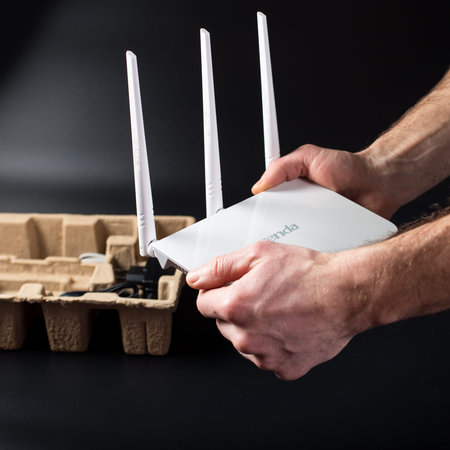 Male hands unpacking brand new WiFi router on black background.