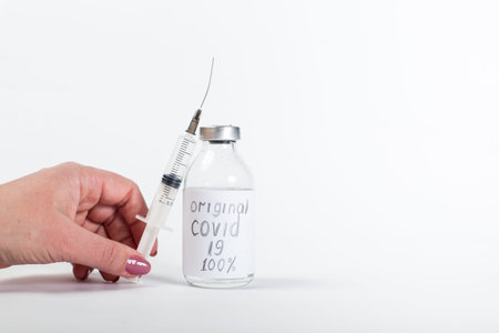 Woman hand holding syringe with fake vaccine, on a white background.
