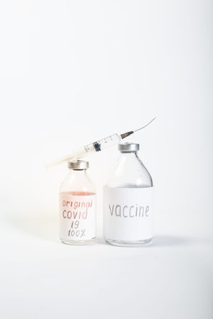 Big bottles of non-certified  vaccine and crooked syringe on a white background.