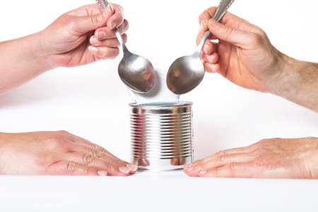 Male and female hands eating from one metal can, on a white background.の写真素材