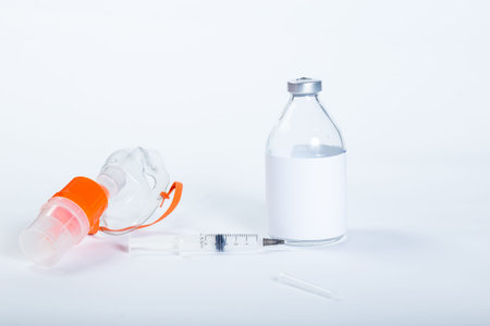 Nebulizer mask with syringe and glass medical bottle on a white background.
