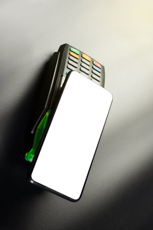 Using smartphone for contactless payment in a shoping, Electronic contacless terminal with cellphone on black background.の写真素材