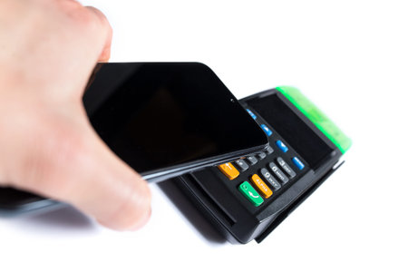 Hand paying with smartphone on contactless terminal isoalted on a white background.