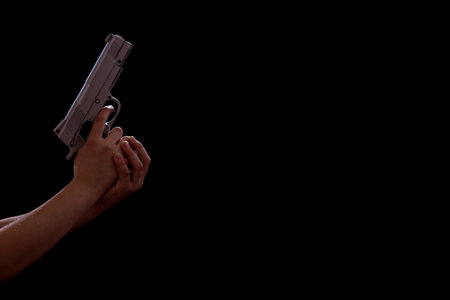 Child's hands holding a gun isolated on black background with copy space.