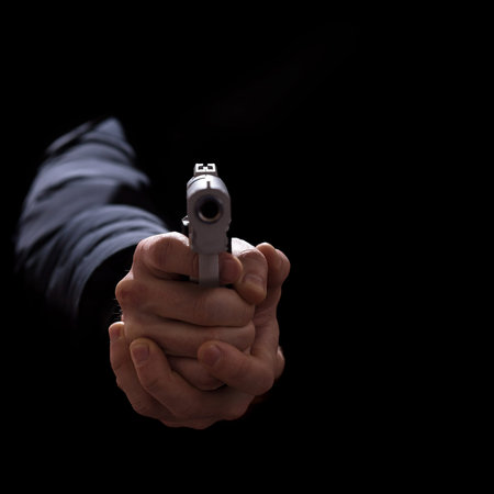 Hands aims with a gun close up, isolated ob a black with copy space.