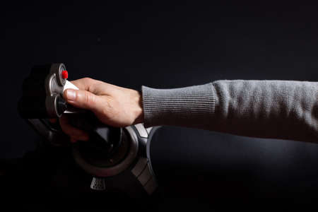 Male hand playing to aircraft shooting game with joystick on black background.の写真素材