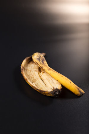 Old brown banana peel close up, on black background.の写真素材
