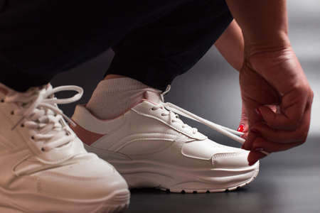 Female hands tying laces on a sport sneakers, close up.の写真素材