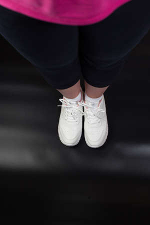 Female foots wearing sport shoes / Foots in pose to make some exercises on black background.の写真素材