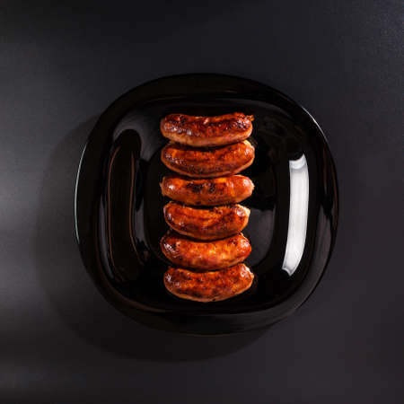 Grilled sausages top view on black background and on black plate.の写真素材