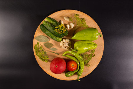 Flat lay of fresh vegetables with spices and herbs on wooden table, on black background.