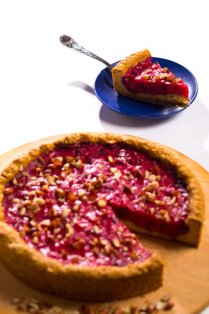 Sweet fruits cake with peanuts and on epiece cutted on little plate, on a white background.