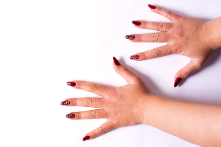 Manicure with red bricks pattern on female hands, on a white background with copy space.の写真素材