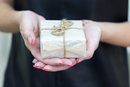 Hands holding craft paper gift box with as a present for Christmas, new year, valentine day or...