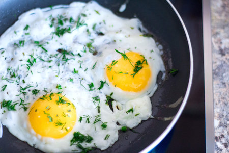 Fried eggs in a frying pan with spices for breakfast on a black background.の写真素材