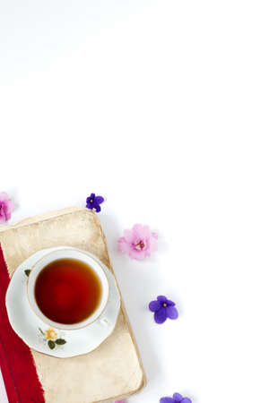 Romantic background with cup of tea ,lilac flowers and retro book over white tableの写真素材