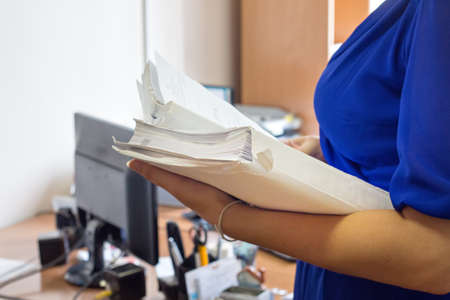 Female office workers holding are arranging documents of unfinished documents on office desk, Stack of business paper.の写真素材