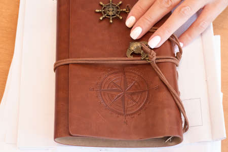 Vintage travel journal in hand on wooden tableの写真素材