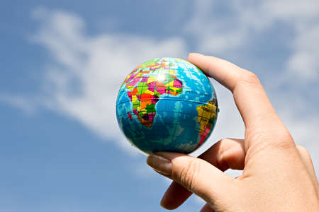 Woman's hand with globe on blue sky backgroundの写真素材