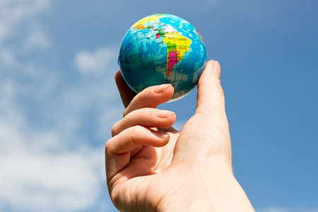 Woman's hand with globe on blue sky backgroundの写真素材
