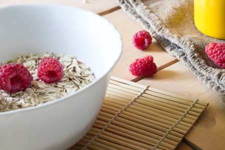 Bowl oatmeal porridge with raspberry and flakes for breakfastの写真素材