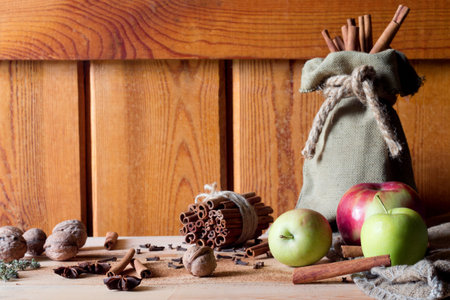 Fresh ripe red apples and cinnamon sticks on wooden background.