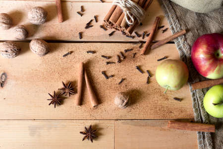 Cinnamon sticks,apples nutmeg and anise on wooden table on brown backgroundの写真素材