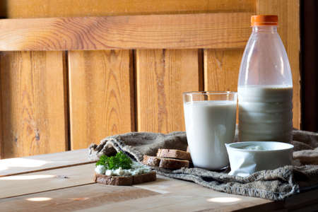Delicious bread with fresh cream cheese and milk on wooden tableの写真素材