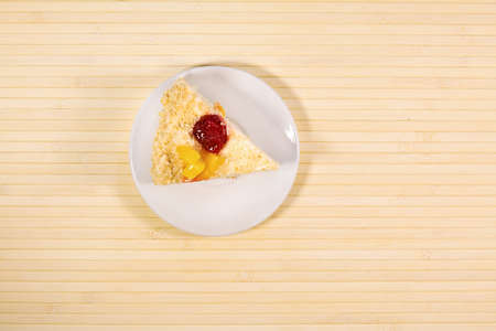 Sliced tasty cake with straberry and peach on wooden light backgroundの写真素材