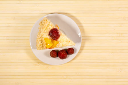 Sliced tasty cake with straberry and peach on wooden light backgroundの写真素材