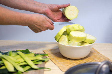 Woman cooking and slicing fresh vegetables on a rustic kitchen worktop, healthy eating concept, flat layの写真素材