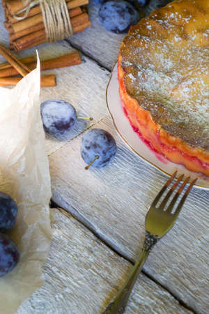 Homemade pie with plums with fork on the white rustic tableの写真素材