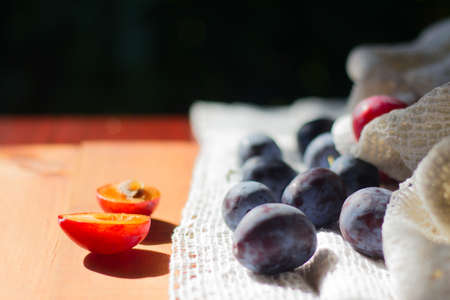 Garden plums on wooden table on green bakground with copy space for textの写真素材