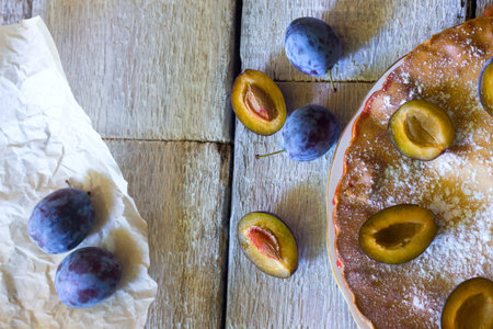 Fresh and warm cake with plum filling and jam. The tart is decorated with powdered sugar. Hot, sweet dough. Rustic wooden table. Autumn, breakfastの写真素材