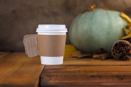 Autumn background with dry leaves and hot paper cup of coffee on wooden tableの写真素材