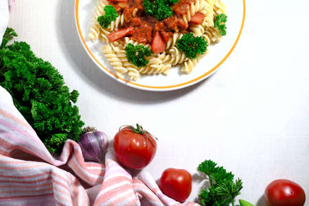 fusilli pasta with tomatoes, parsley and sweet pepper on white background. Top viewの写真素材